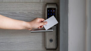 Person holding a white access card to a digital lock with a keypad and keyhole option.
